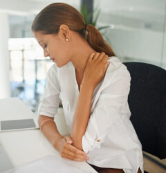 Shot of a young businesswoman experiencing neck and shoulder pain at work