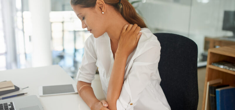 Shot of a young businesswoman experiencing neck and shoulder pain at work