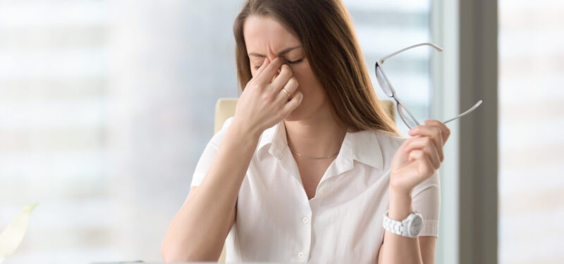 Tired businesswoman holding eyeglasses and massaging nose bridge. Girl feeling discomfort from long wearing glasses at workplace. Exhausted female office worker gather herself for completing work